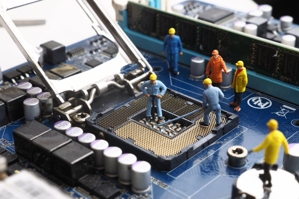 Miniature construction worker figurines are placed on a computer motherboard