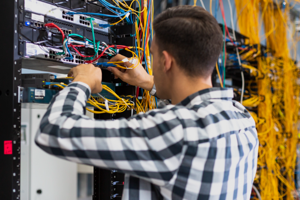 Technician working on a server rack with multiple colored network cables.