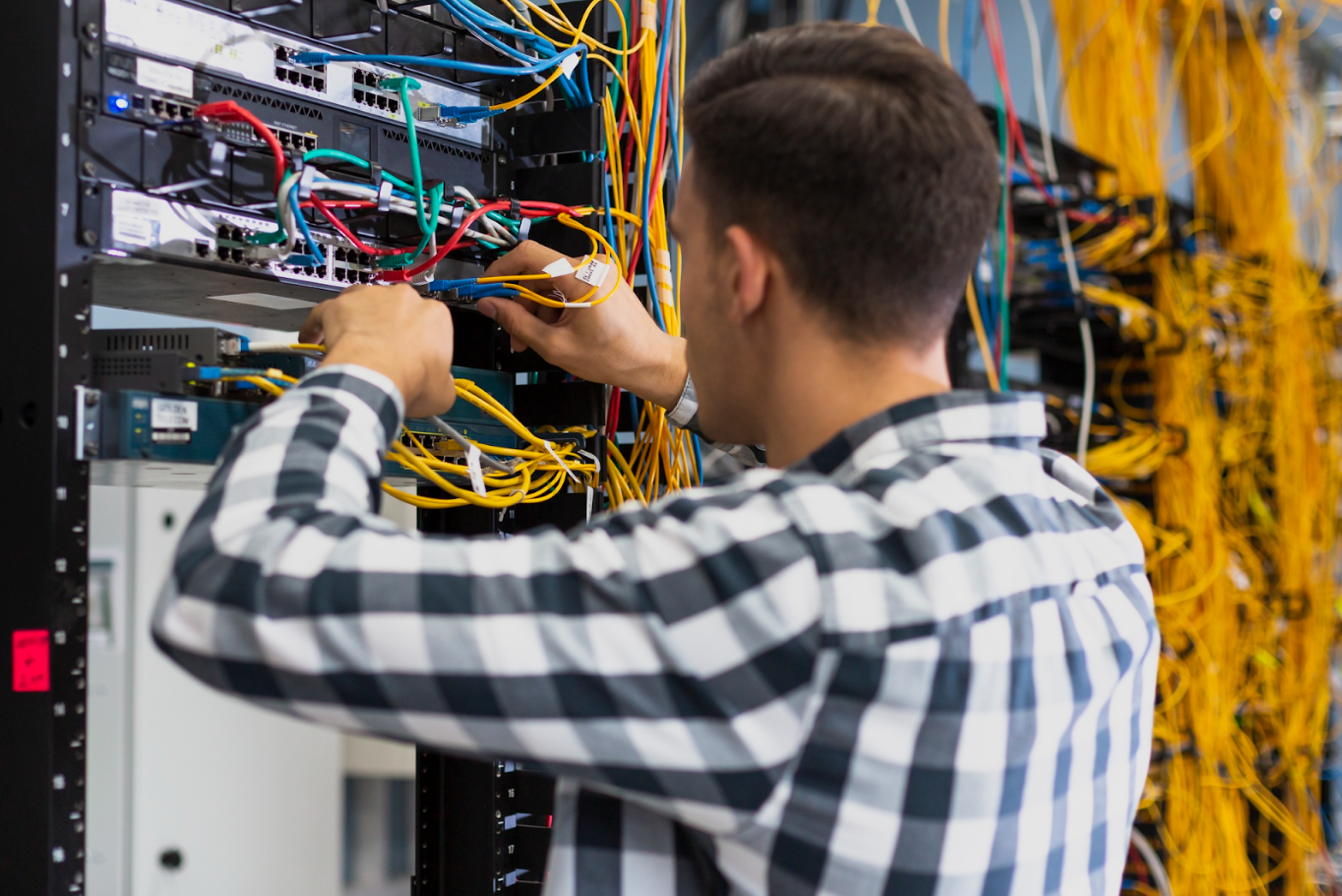 Technician connecting cables to a server rack during hardware setup.