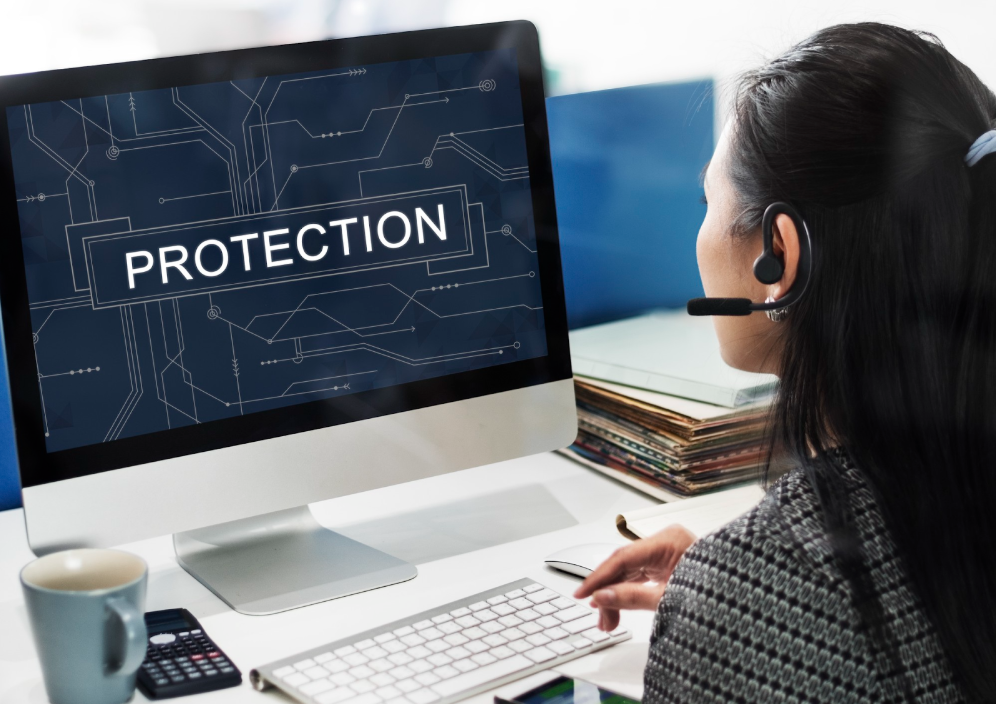  Woman using a desktop computer showing the word "Protection" on screen.